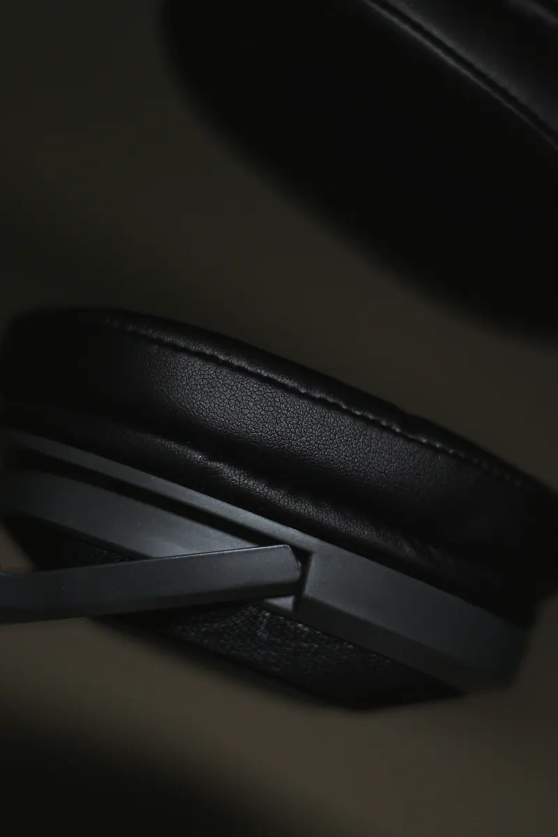 Close-up of a leather earpad and matte yoke on an over-ear headphone in low light